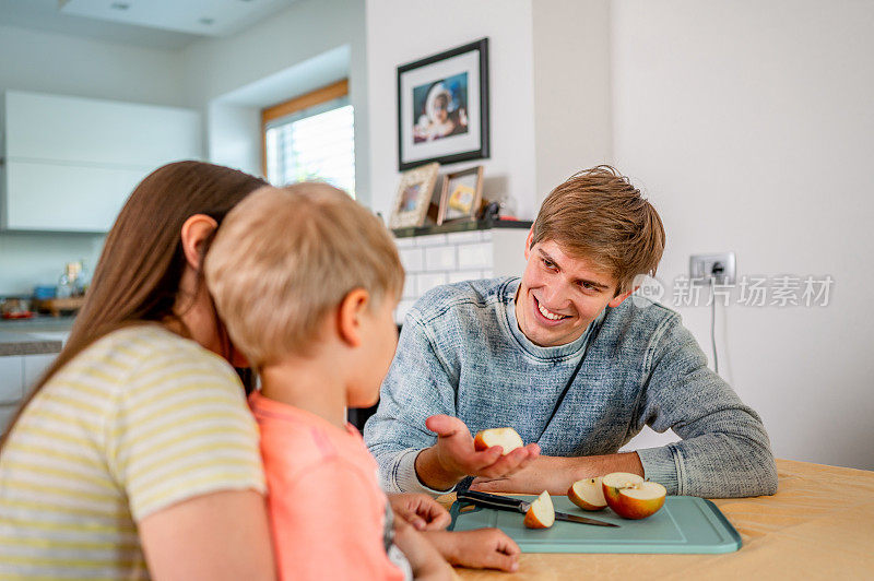 Young family having an apple for a snack in a dining room